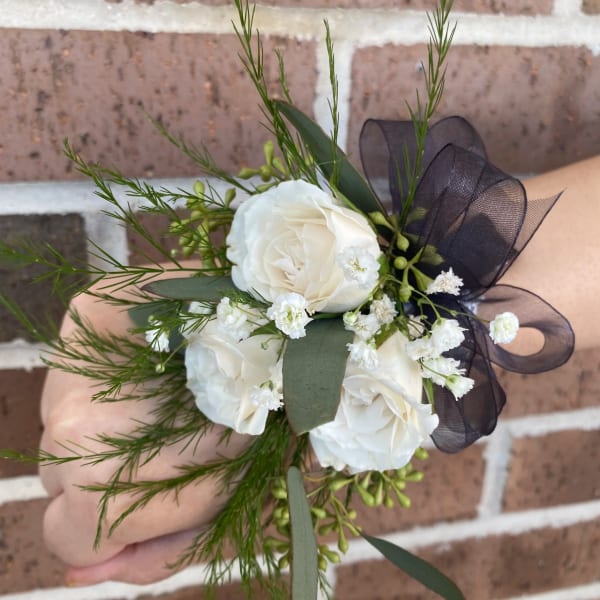 White rose wrist corsage with black ribbon and greenery