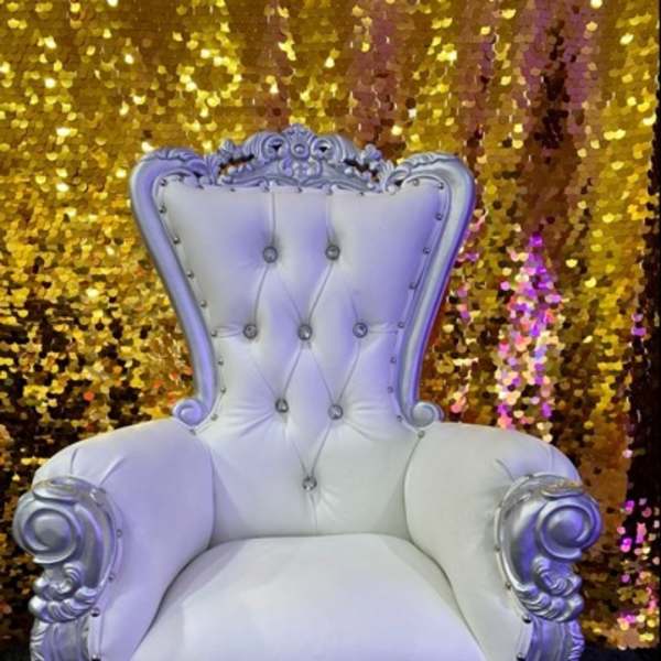Ornate white tufted throne chair in front of a gold sequin backdrop
