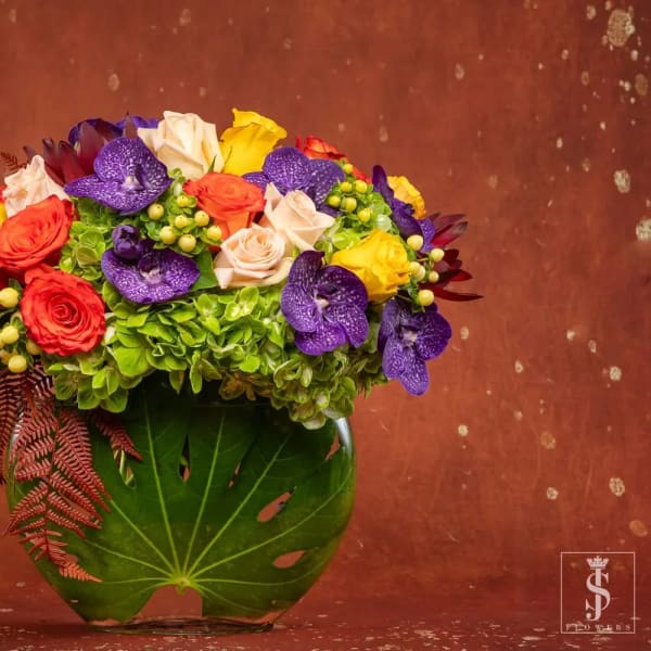 Mixed bouquet of roses, orchids, and hydrangeas in a glass vase