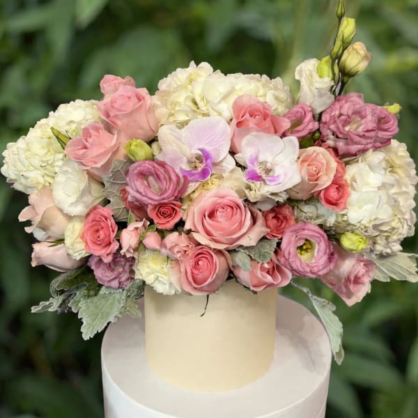 Pink and white floral arrangement in a cream hatbox