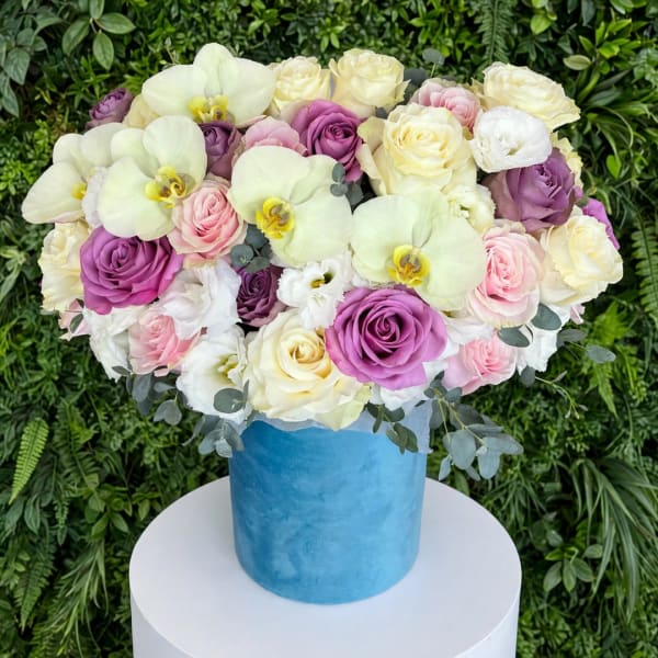 Mixed bouquet of roses and white orchids in a blue hatbox