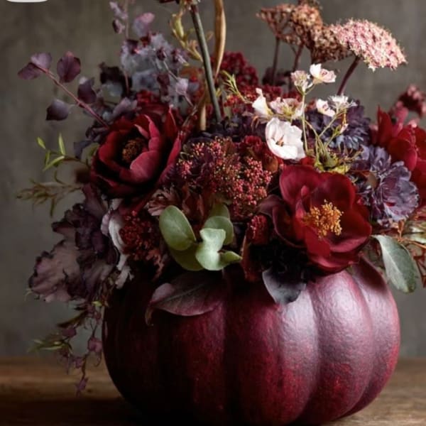 Dark red floral arrangement in a metallic pumpkin container