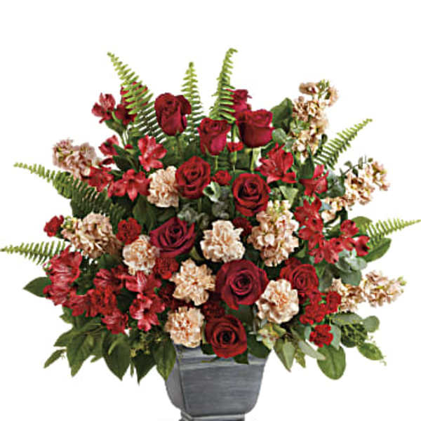 Red roses and carnations arranged in a gray urn vase