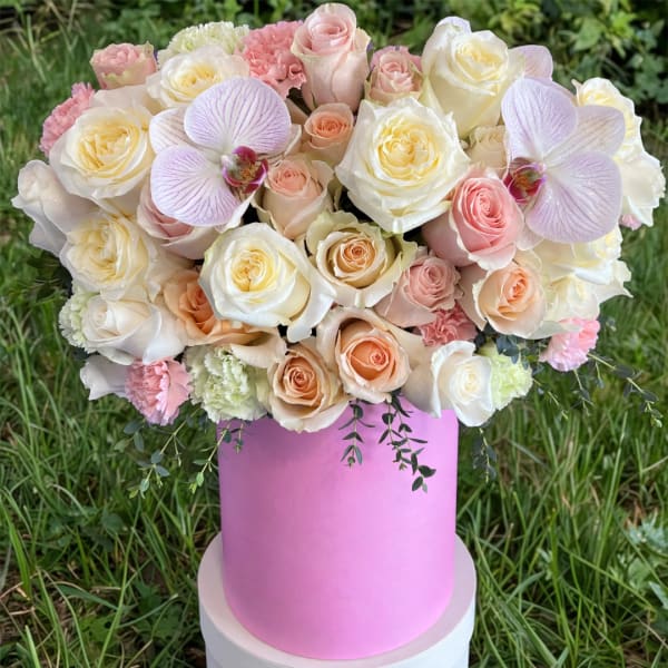 Pink and cream rose bouquet in a pink hat box with orchid accents