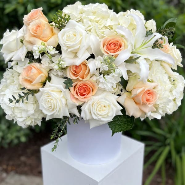 White and peach roses with white lilies in a white vase