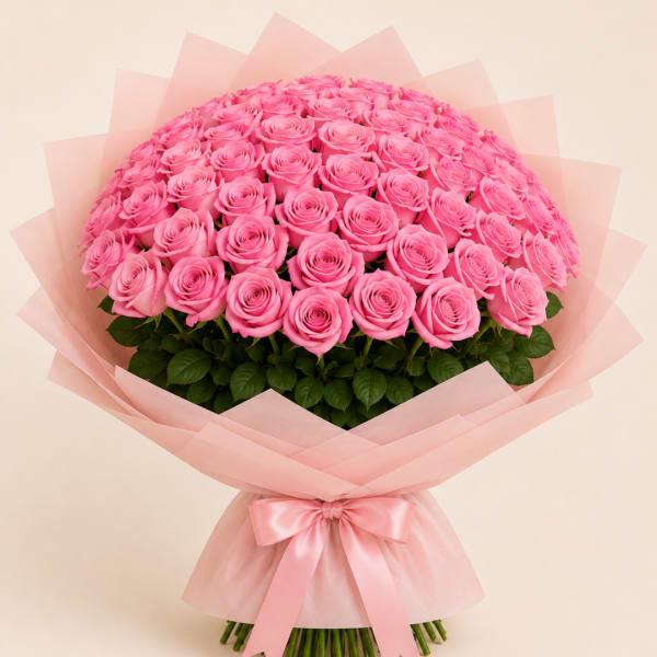 Large bouquet of pink roses wrapped in pale pink paper with a satin bow