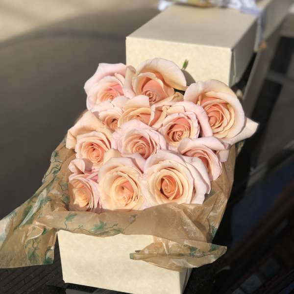 Bouquet of pale peach roses wrapped in brown paper
