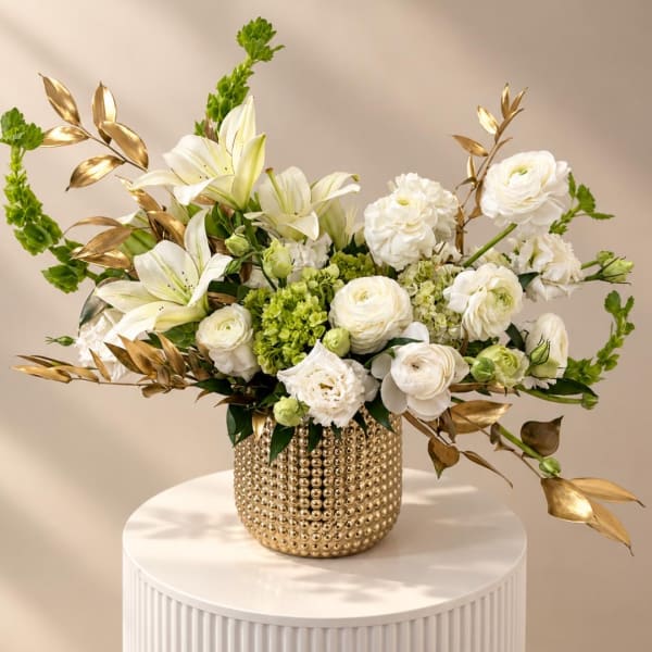 White floral arrangement in a gold textured vase with gold leaf accents