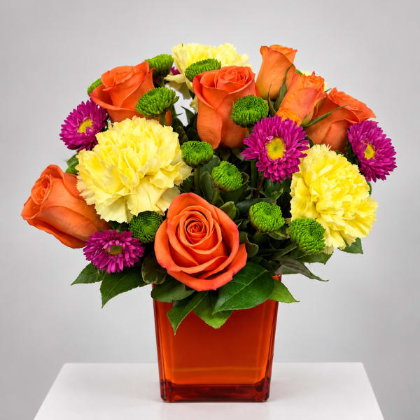 Orange roses, yellow carnations, and purple daisies in an orange vase