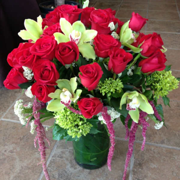 Bouquet of red roses and green orchids in a glass vase