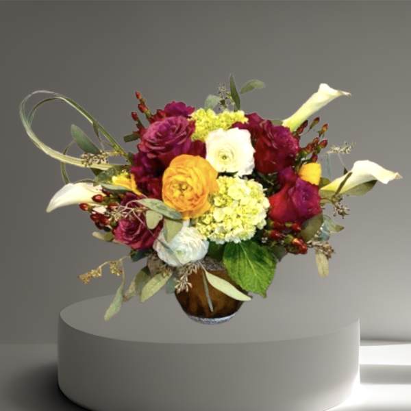 Mixed bouquet with calla lilies, roses, and hydrangeas in a glass vase