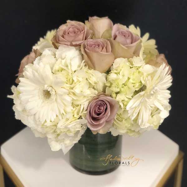 Bouquet of blush roses and white daisies in a green vase
