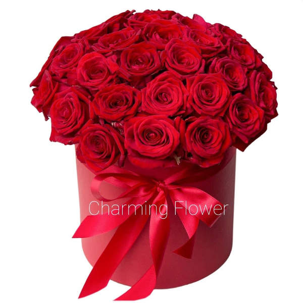 Red roses arranged in a round hatbox with a satin ribbon