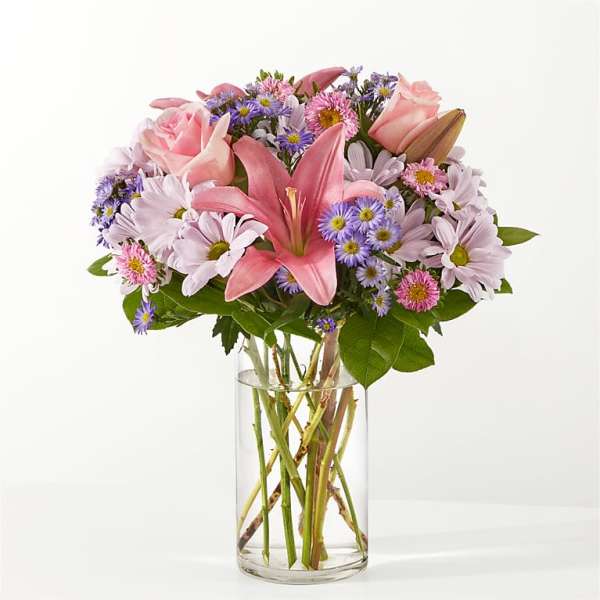 Pink lilies and daisies in a clear glass vase