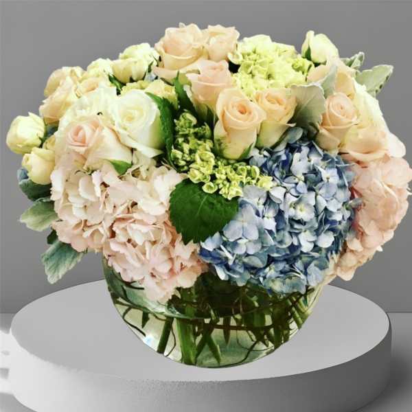 Pastel roses and hydrangeas arranged in a clear glass vase
