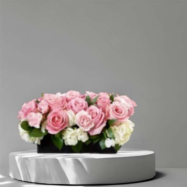 Pink and white rose arrangement in a black rectangular container