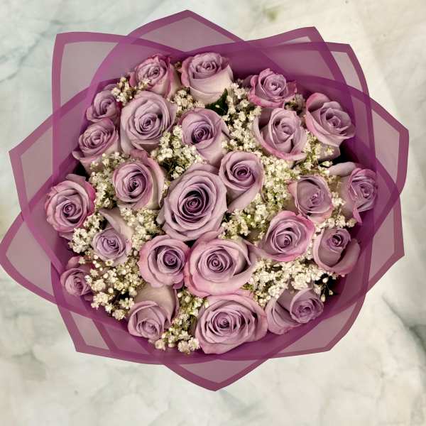 Bouquet of lavender roses with white filler flowers wrapped in purple paper