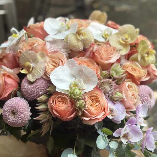 Bouquet of peach roses with white orchids and lavender pompon flowers