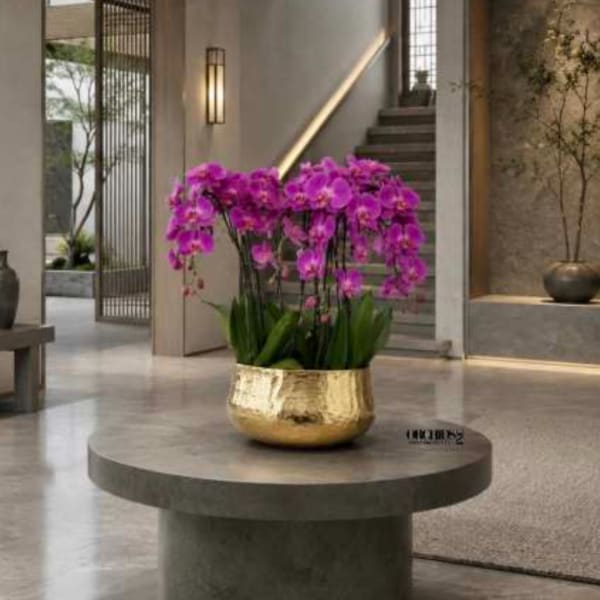 Purple orchids in a gold vase on a round table