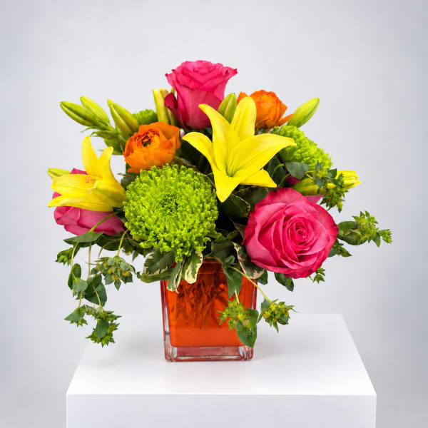 Bright mixed bouquet of roses, lilies, and green chrysanthemums in an orange vase