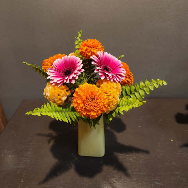 Pink gerbera daisies and orange marigolds in a small vase