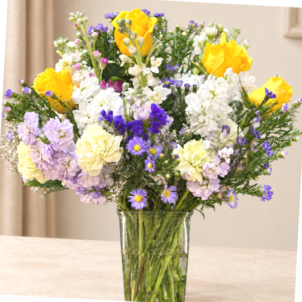 Mixed bouquet of yellow, white, purple, and lavender flowers in a glass vase