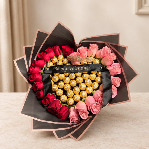 Heart-shaped bouquet of red and pink roses with chocolates and a ribbon