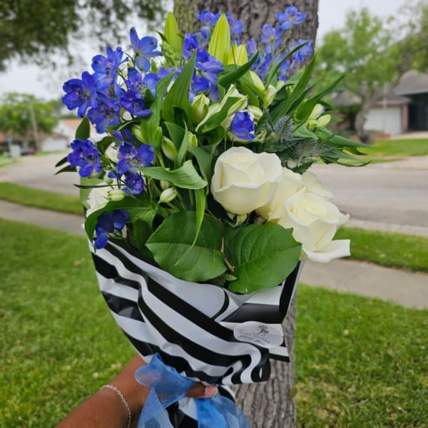 Bouquet of white roses and blue flowers wrapped in black-and-white paper