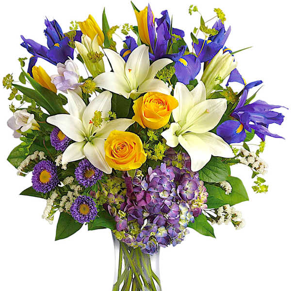 Bouquet of white lilies, yellow roses, and purple flowers in a glass vase