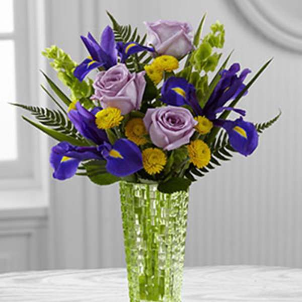 Purple roses and irises in a clear glass vase