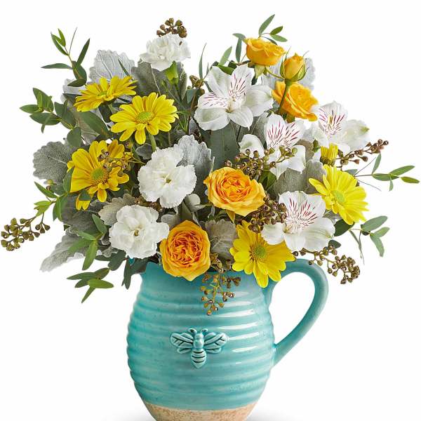 Yellow and white flowers arranged in a turquoise mug vase