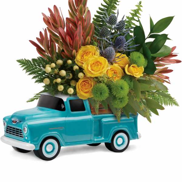 Yellow roses arranged in a turquoise ceramic truck
