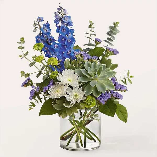 Blue and white flowers arranged in a clear glass vase with a succulent
