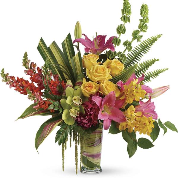 Mixed bouquet of pink lilies, yellow roses, and orchids in a glass vase