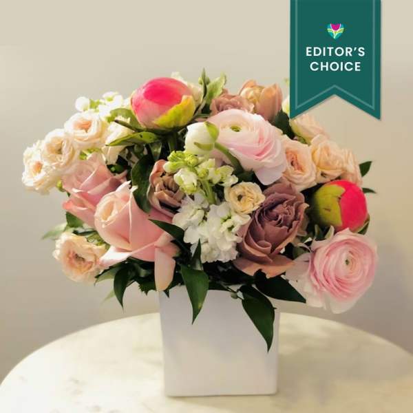 Pink and cream bouquet in a white vase with an editor's choice ribbon
