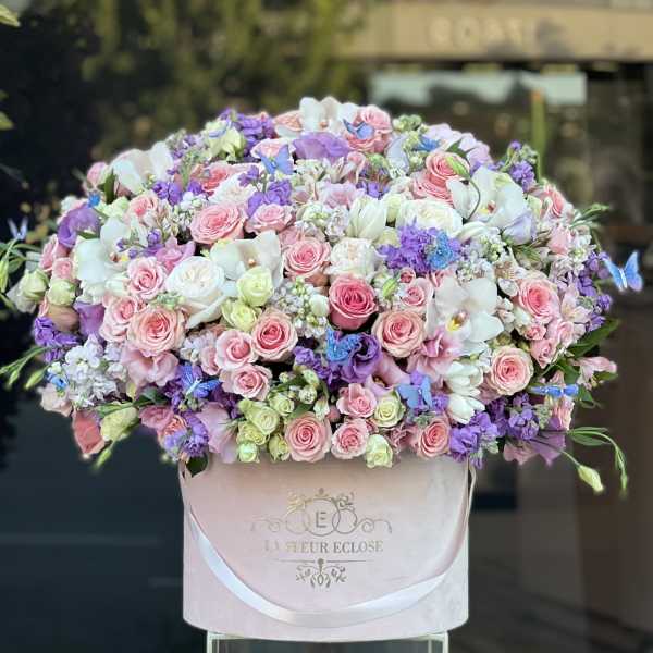 Large pastel bouquet of pink, white, and purple flowers in a pink box