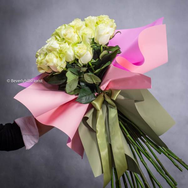 Bouquet of pale yellow roses wrapped in pink paper with a ribbon