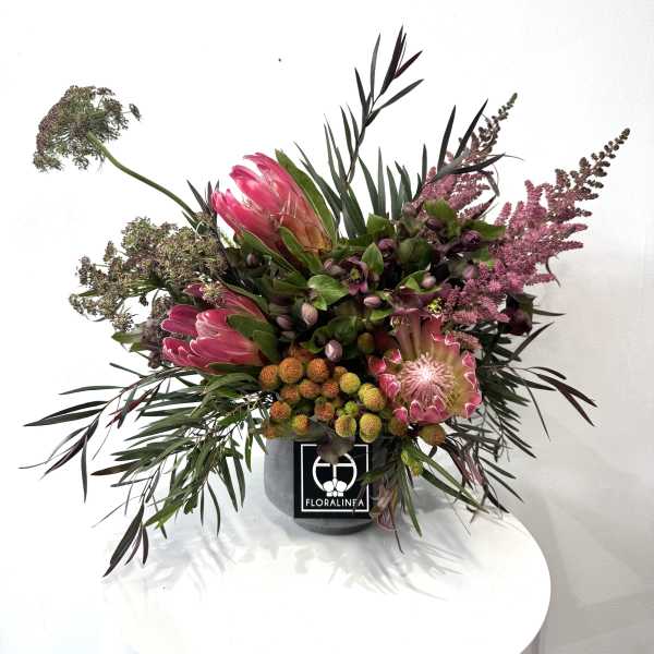 Pink protea arrangement in a gray container
