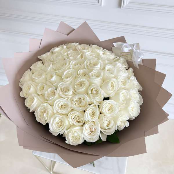 Large bouquet of white roses wrapped in blush paper
