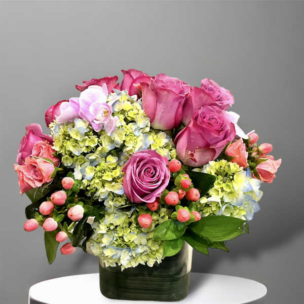 Pink roses and hydrangeas arranged in a dark glass vase