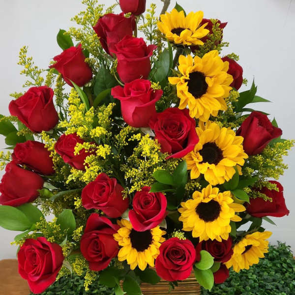 Bouquet of red roses and yellow sunflowers in a woven basket