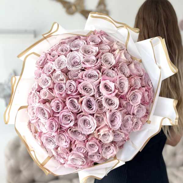 Large bouquet of pale pink roses wrapped in white paper with gold trim