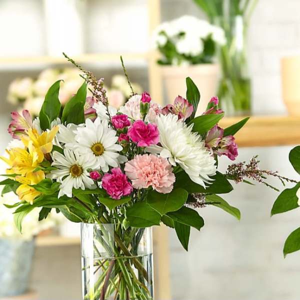 Mixed bouquet of daisies, carnations, and alstroemeria in a clear glass vase