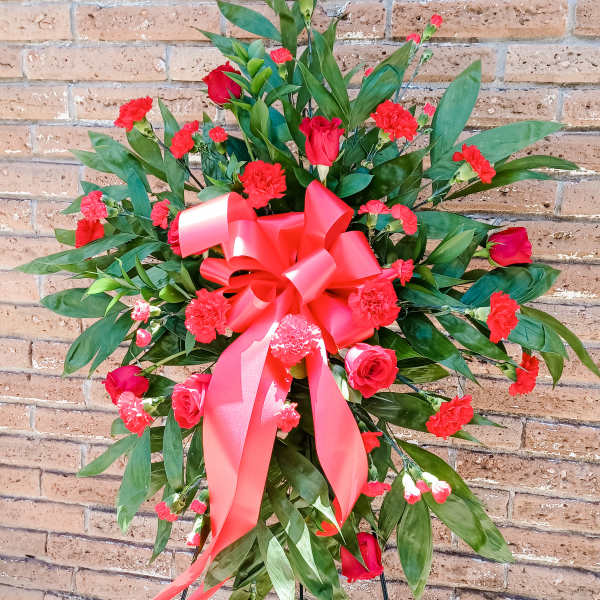 Standing floral spray with red roses and carnations, tied with a large red ribbon