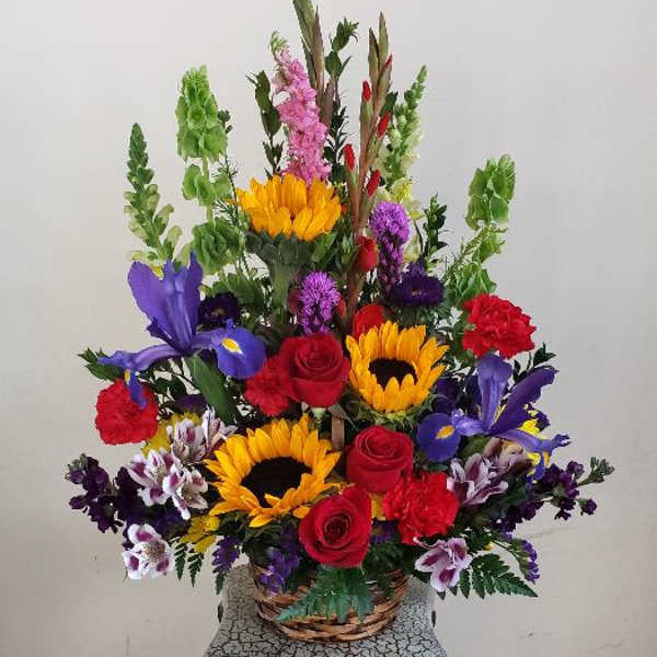 Colorful mixed flower arrangement in a wicker basket on a pedestal