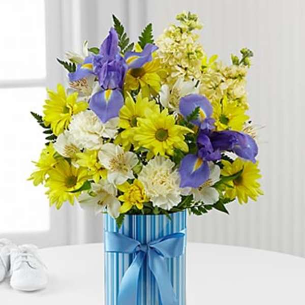 Bouquet of yellow, white, and purple flowers in a blue striped box