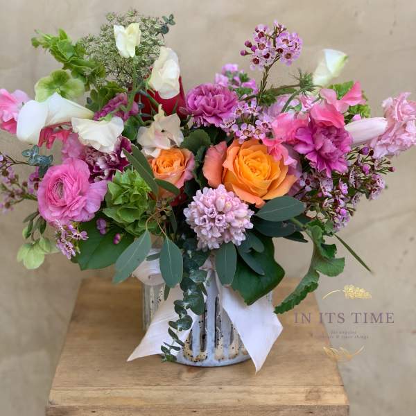 Mixed bouquet of pink, orange, and white flowers in a ceramic vase