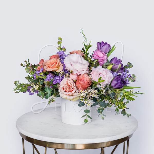 Pastel floral arrangement in a white vase with pink and purple blooms
