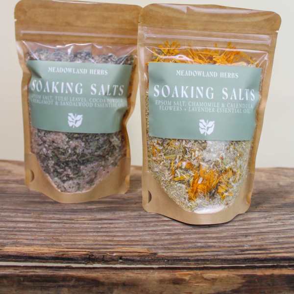 Two pouches of soaking salts with dried flowers on a wooden surface