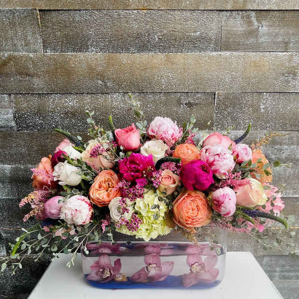 Mixed pink and peach flower arrangement in a rectangular glass vase